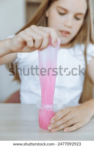 Adorable little girl holding a slime toy, a popular homemade toy all over the world. A child plays with slime and stretches it.