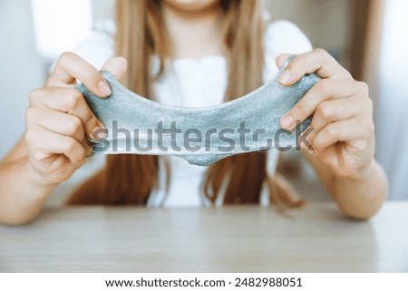 Adorable little girl holding a slime toy, a popular homemade toy all over the world. A child plays with slime and stretches it.