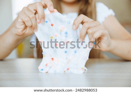 Adorable little girl holding a slime toy, a popular homemade toy all over the world. A child plays with slime and stretches it.