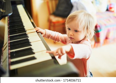 Adorable Little Girl Playing Piano. Toddler Having Fun While Learning How To Play Music. Musical Education For Small Kids