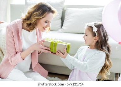 Adorable Little Girl Presenting Gift To Happy Mother On Mothers Day