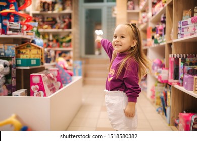 Adorable little girl shopping for toys. Cute female in toy store. Happy young girl selecting toy - Shutterstock ID 1518580382