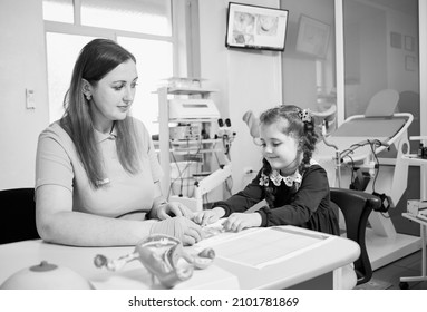 Adorable little girl studying female reproductive system with lovely doctor in gynecological cabinet. Concept of gynecology, study and female reproductive system. Monochrome image.