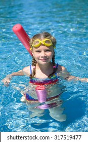 Adorable Little Girl Swimming With A Pink Foam Noodle In A Pool 