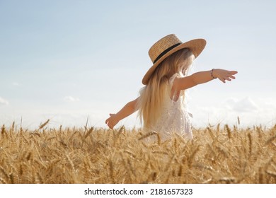 Adorable little girl in white dress in a wheat field