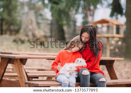 Adorable little girl and young mother with puppy outdoor