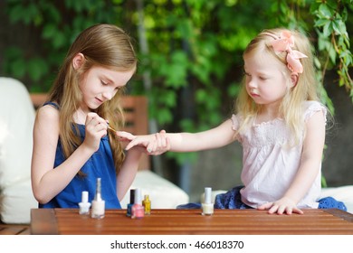 Adorable Little Girls Having Fun Playing At Home With Colorful Nail Polish Doing Manicure And Painting Nails To Each Other