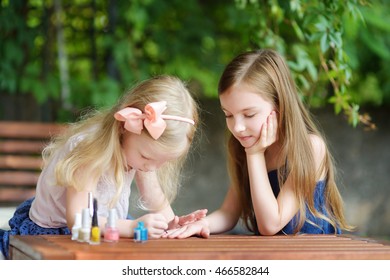 Adorable Little Girls Having Fun Playing At Home With Colorful Nail Polish Doing Manicure And Painting Nails To Each Other