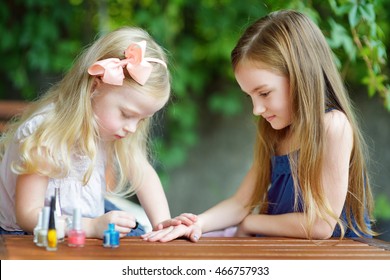 Adorable Little Girls Having Fun Playing At Home With Colorful Nail Polish Doing Manicure And Painting Nails To Each Other