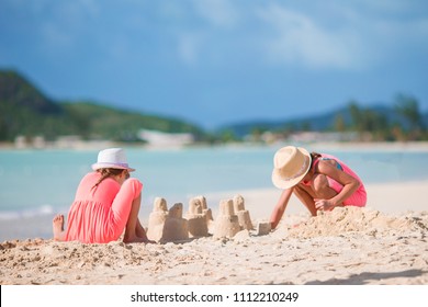 Adorable little girls playing on the beach with toys during summer vacation