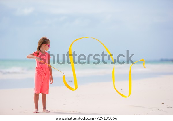Adorable little gymnast dancing with with\
gymnastic ribbon