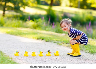 Adorable little kid girl playing in forest playground with yellow rubber ducks. Cute child wearing rain boots. Active leisure with kids. - Shutterstock ID 392151763
