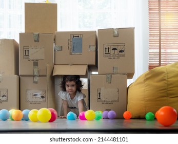 Adorable little toddler girl crawling through empty boxes when unpacking when moving house.