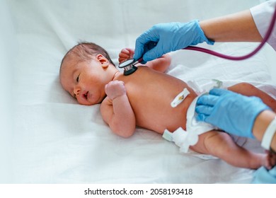 Adorable Newborn Baby Boy In Diaper Check Up Examines By Pediatrician Doctor. Unrecognizable Doctor Hand Using Stethoscope Examining Little Cute Baby Infant Heart, Lung In Clinic. Health Care Concept.