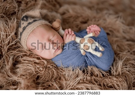 Adorable newborn baby boy smiling during sleeping and holding knitted giraffe toy. Cute infant child kid napping on fur
