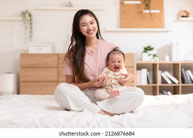 Adorable newborn baby smile and relax in mother arm safety and comfortable.Healthy Asian newborn infant baby laughing with happiness good moment.Mother holding infant baby.Newborn Baby concept