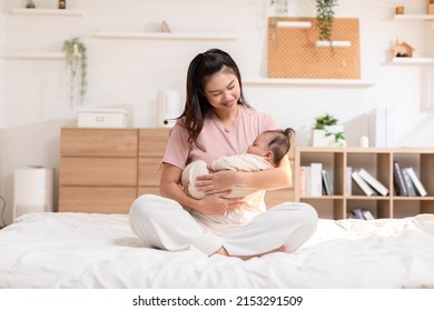 Adorable newborn baby smile and relax in mother arm safety and comfortable. Healthy Asian newborn infant baby laughing with happiness good moment. Mother holding infant baby. Newborn Baby concept