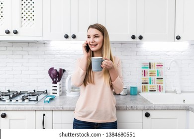 Adorable Nice Charming Beautiful Trendy Stylish Girl Drinking Coffee In Modern Light White Kitchen, Talking On Mobile Phone