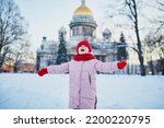 Adorable preschooler girl having fun in beautiful winter park on a snowy cold winter day. Cute child playing in snow. Winter activities for family with kids