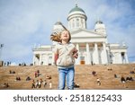 Adorable preschooler girl near Helsinki Cathedral (Helsingin tuomiokirkko) on Senaatintori in Helsinki, Finland