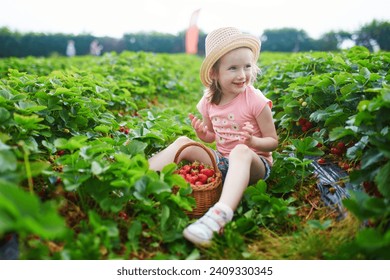 Adorable preschooler girl picking fresh organic strawberries on farm. Delicious healthy snack for small children. Outdoor summer activities for little kids - Powered by Shutterstock