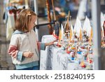 Adorable preschooler girl selecting small wooden boats on market in Helsinki, Finland