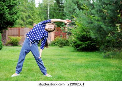 Adorable preteen girl doing exercise outdoors on the lawn - Powered by Shutterstock