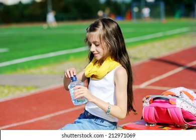 Adorable Preteen Girl In Fashion Outfit  Drinking Water At The School Athletic Field