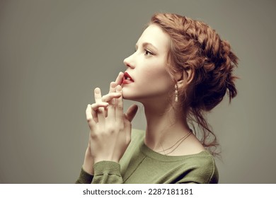 Adorable red-haired girl fashion model with delicate make-up and curly red hair poses in an olive dress on a gray studio background. Copy space. Fashion and beauty. Makeup and cosmetics, hairstyle. - Shutterstock ID 2287181181