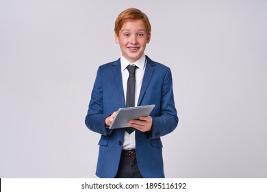 Adorable redhead young school boy in formal attire with braces using tablet isolated over grey background - Powered by Shutterstock