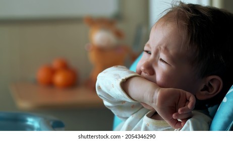 Adorable Sad Caucasian Baby Crying In High Chair In Kitchen. Portrait Of Upset Toddler Boy Cry Having Meal In Kitchen