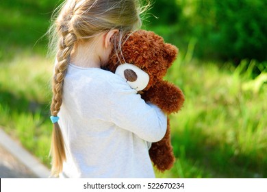 Adorable Sad Girl With Teddy Bear In Park.