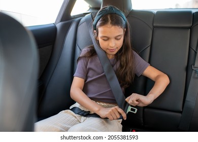 Adorable schoolgirl fastening seatbelt while sitting inside electric car - Powered by Shutterstock