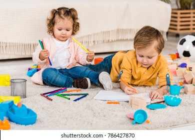 adorable siblings drawing on a floor with colored pencils - Shutterstock ID 786427870