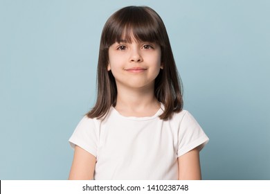 Adorable Six Years Old Girl In White T-shirt Isolated On Blue Studio Background, Pretty Brown-haired Fringe Hairstyle European Appearance Child Pose Indoor Smiling Look At Camera, Generation Z Concept