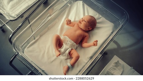Adorable Small Caucasian Newborn Child Lying in Hospital Bed in a Nursery Clinic. Little Playful and Healthy Baby. Medical Health Care, Maternity and Parenthood Concept. High Angle Close Up Portrait