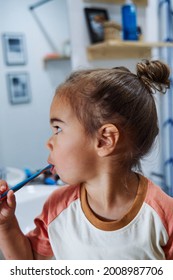 An Adorable Spanish Baby Girl Washing Her Teeth In The Bathroom