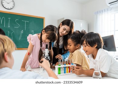 Adorable student learn with teacher in classroom at elementary school. Young brilliant and smart children sit on table and study chemistry experiment with happiness and fun activity at kindergarten. - Powered by Shutterstock