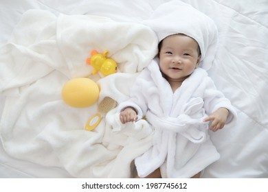 Adorable sweet Asian baby girl wrapped in white bathrobe and  bath turban , baby bath time concept