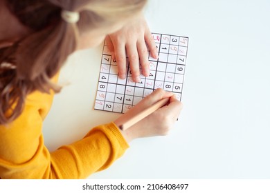 Adorable teen girl solving sudoku at desk at school or at home. View from above - Powered by Shutterstock