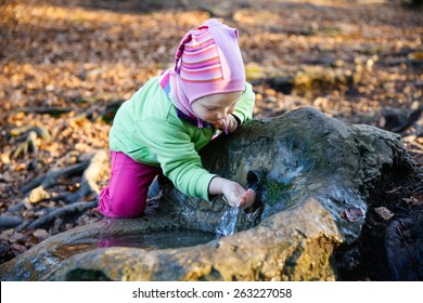 Adorable, Thirsty Little Girl Drinking Clean Spring Water From A Source In A Forest