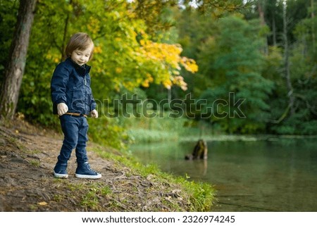 Adorable toddler boy admiring the Balsys lake, one of six Green Lakes, located in Verkiai Regional Park. Child exploring nature on autumn day in Vilnius, Lithuania. Fun autumn activities for kids.