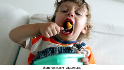 Adorable toddler boy eating healthy fruit snack with fork