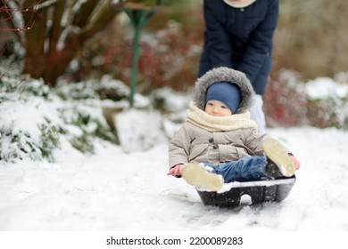 Adorable Toddler Boy Having Fun In A Backyard On Snowy Winter Day. Cute Child Wearing Warm Clothes Playing In A Snow. Winter Activities For Family With Kids.