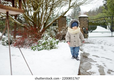 Adorable Toddler Boy Having Fun In A Backyard On Snowy Winter Day. Cute Child Wearing Warm Clothes Playing In A Snow. Winter Activities For Family With Kids.