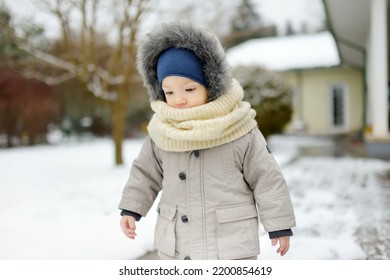 Adorable Toddler Boy Having Fun In A Backyard On Snowy Winter Day. Cute Child Wearing Warm Clothes Playing In A Snow. Winter Activities For Family With Kids.