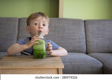 adorable toddler drinking a green smoothie