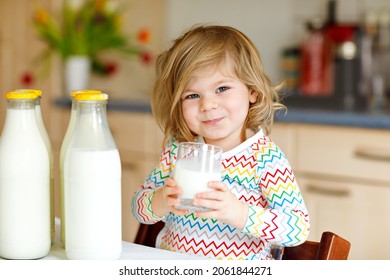 Adorable Toddler Girl Drinking Cow Milk For Breakfast. Cute Baby Daughter With Lots Of Bottles. Healthy Child Having Milk As Health Calcium Source. Kid At Home Or Nursery In The Morning.