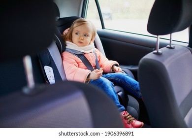 Adorable Toddler Girl In Modern Car Seat Eating Cookie. Little Kid Traveling By Car. Child Safety On The Road. Trip With A Baby