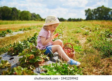 Adorable toddler girl in straw hat picking fresh organic strawberries on farm. Delicious healthy snack for small children. Outdoor summer activities for little kids - Powered by Shutterstock